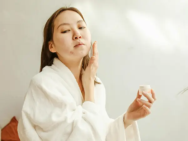 Perempuan menggunakan make up atau skin care